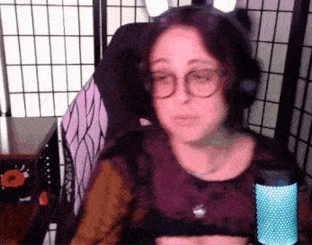a woman wearing glasses and headphones is talking into a microphone .