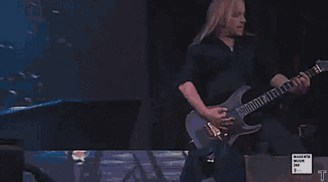 a man playing a guitar in front of a magenta music sign