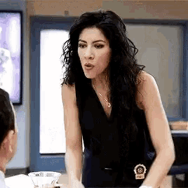 a woman in a black tank top is talking to a man in a blue room .