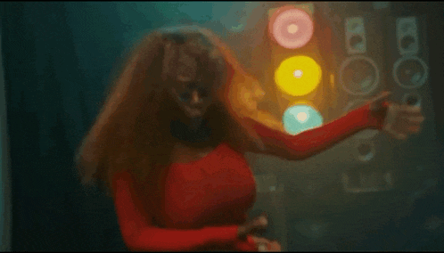 a woman in a red shirt is dancing in a dark room in front of speakers .