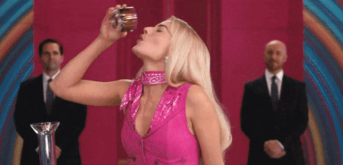 a woman in a pink dress is drinking from a glass