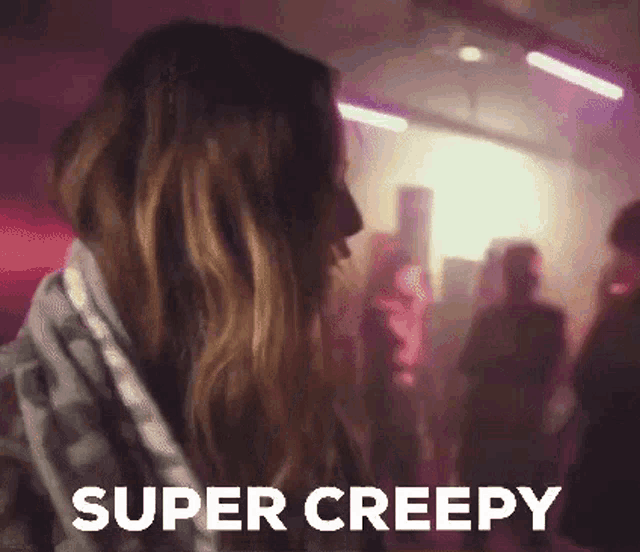 a woman is dancing in a dark room with the words `` super creepy '' written on the bottom of her face .