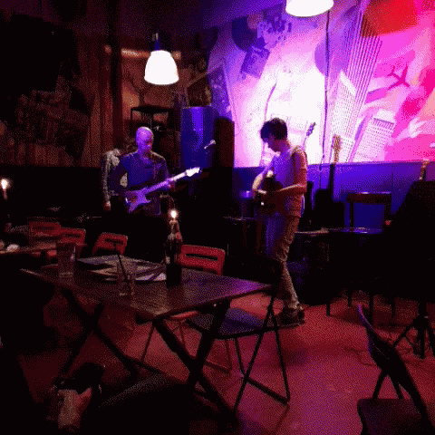 two men playing guitars in a dark room