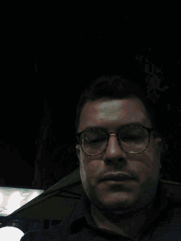 a man with glasses and a beard looks down at something
