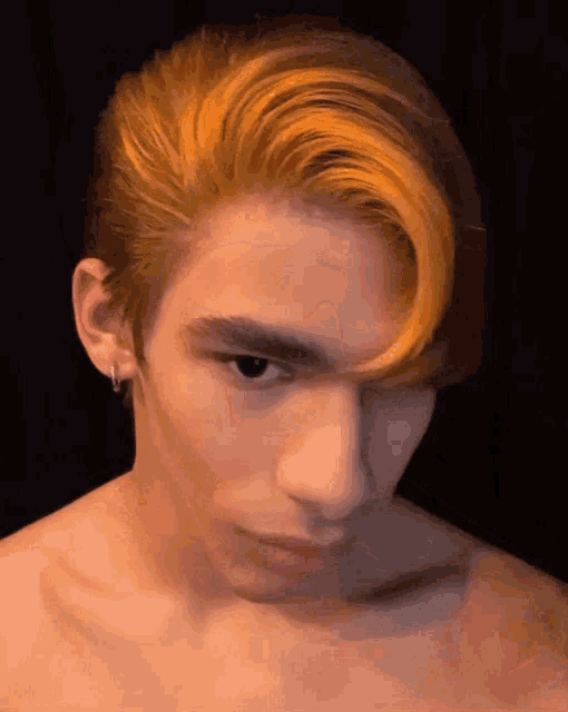a man without a shirt has orange hair and earrings