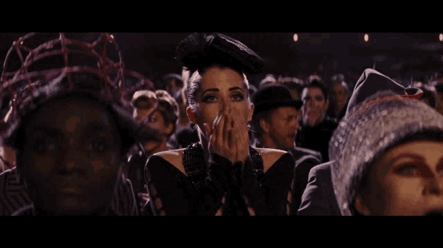 a woman is covering her face with her hands in a crowd of people