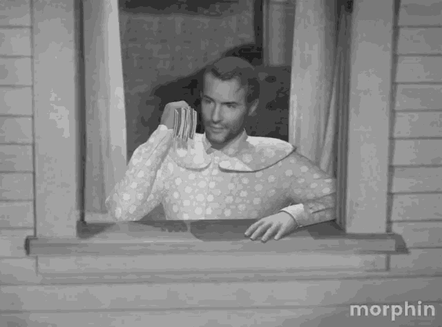 a black and white photo of a man in a diaper looking out a window