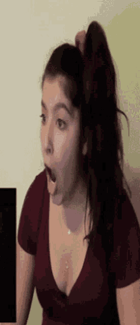 a woman with a ponytail is making a surprised face .
