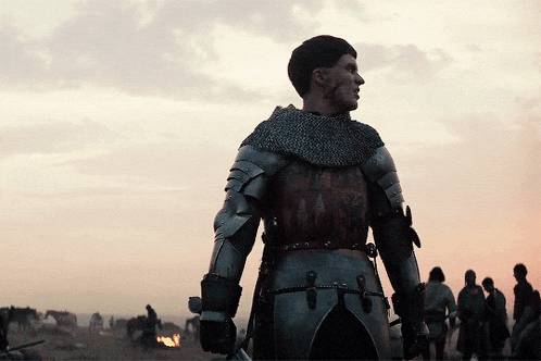 a man in armor holds a sword in front of a group of people