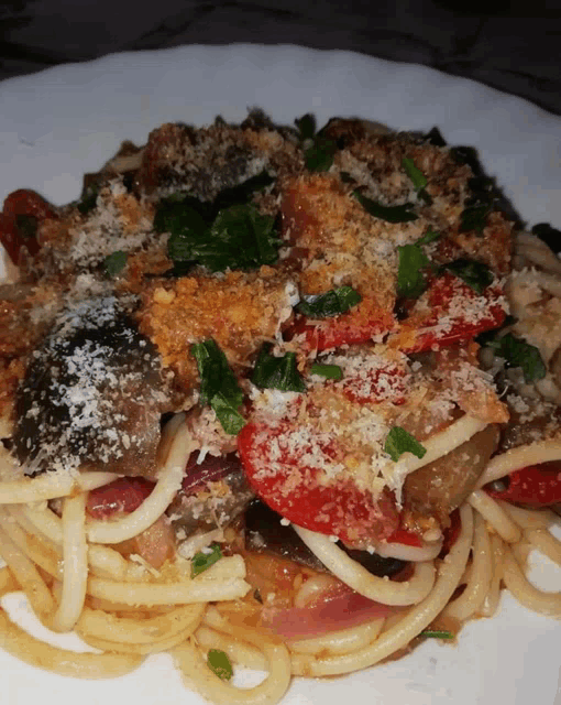 a white plate topped with spaghetti and vegetables with cheese on top