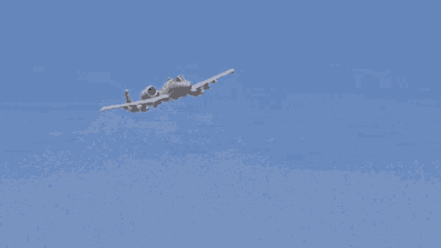 a fighter jet is flying in a blue sky with a smoke trail behind it