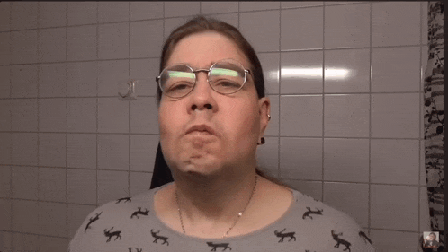 a man wearing glasses and a shirt with frogs on it makes a face