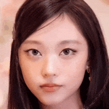 a close up of a woman 's face with long dark hair and a piercing in her nose .