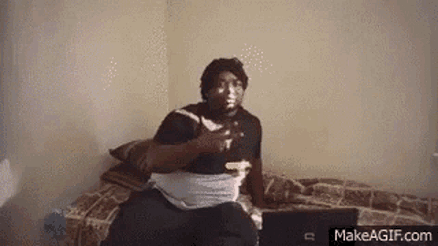 a man is sitting on a bed with a laptop and a bottle of water .