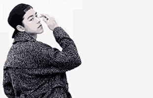 a black and white photo of a young man wearing a hat and a sweater .