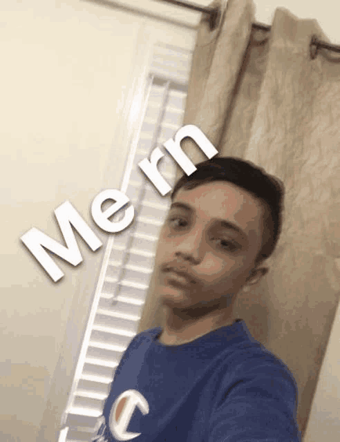 a young boy is taking a selfie in front of a window with a caption that says `` me rn '' .
