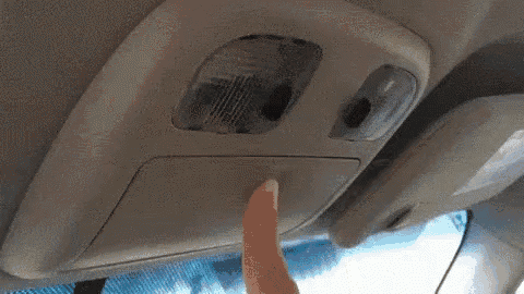 a person is pressing a button on the roof of a car .