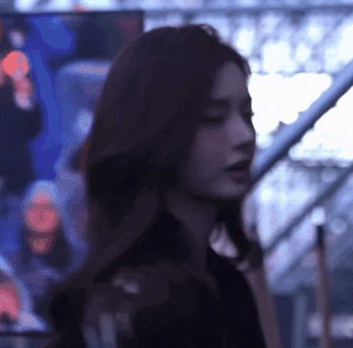 a woman with long hair is standing in front of a blurry background