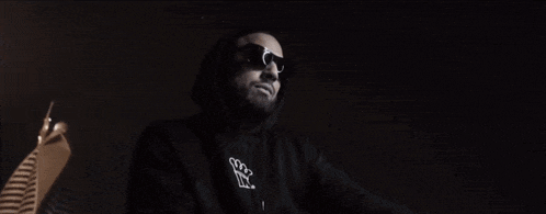 a man with a beard wearing sunglasses and a hoodie that says ' sss ' on it