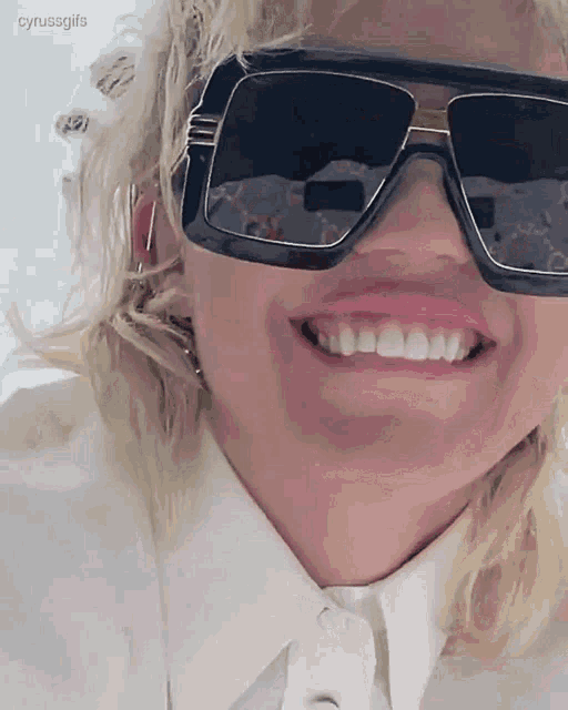a close up of a woman wearing sunglasses and a white shirt