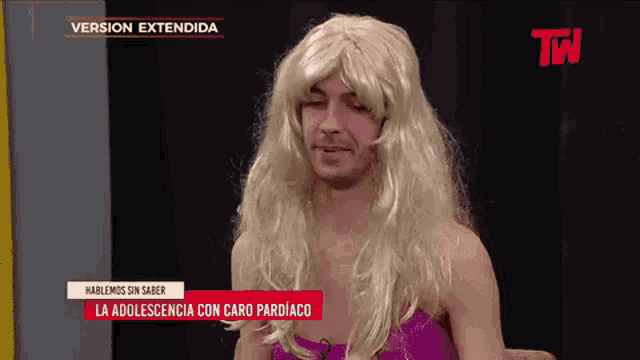 a man wearing a blonde wig and a pink top is on a tv show called version extendida
