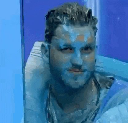 a man with blue paint on his face is sitting in a container of water .