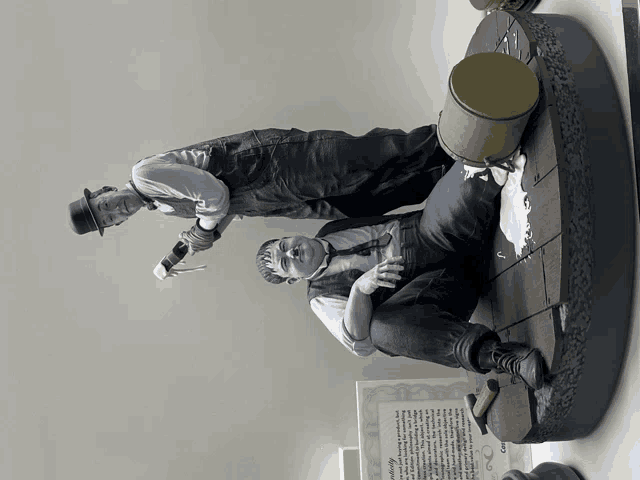 a statue of three men sitting next to each other with a certificate behind them