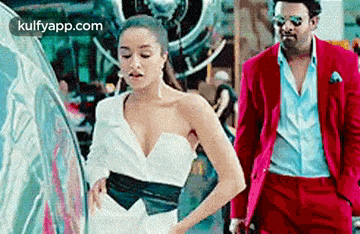 a man in a red suit and a woman in a white dress are standing next to each other .