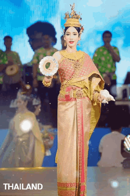 a woman in a thailand costume holds a fan in her hand