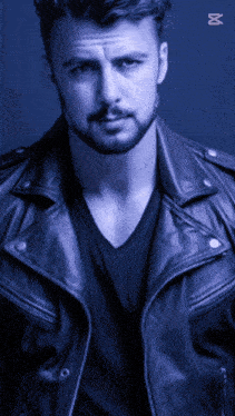 a man with a beard is wearing a leather jacket and a black shirt