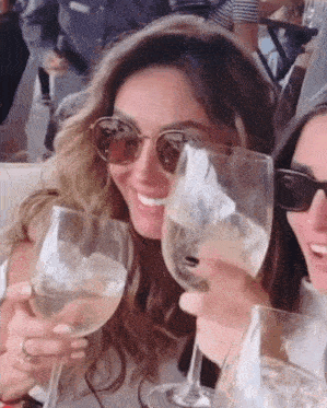 a woman wearing sunglasses is holding two wine glasses