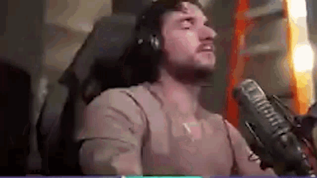 a man wearing headphones and a microphone is sitting in a chair .