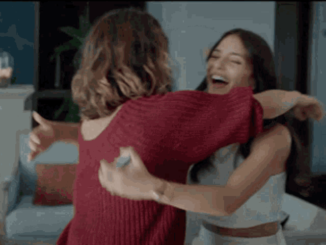 two women are hugging each other in a living room