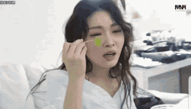 a woman is eating a grape with a toothpick on her face .