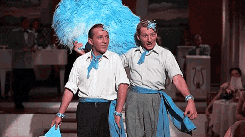 two men are standing next to each other with one wearing a blue and white feathered headpiece