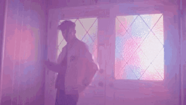 a man is dancing in front of a stained glass door in a room with purple lights .