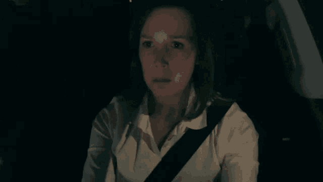 a woman wearing a seat belt is sitting in a car