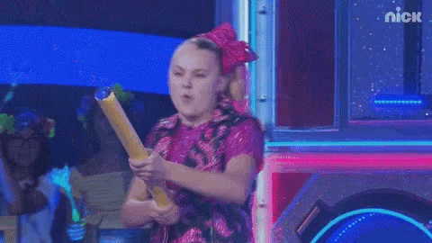 a girl in a pink dress is holding a yellow object in her hands .