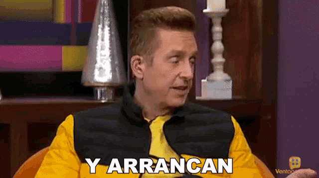 a man in a yellow vest says y arrancan while sitting in a chair