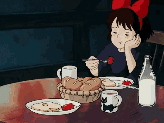 a girl with a red bow on her head sits at a table eating