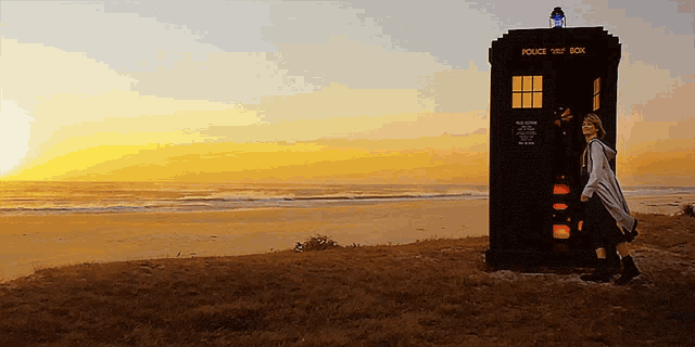 a woman stands in front of a police box
