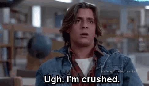 a man in a denim jacket is sitting in a library and saying ugh , i 'm crushed .