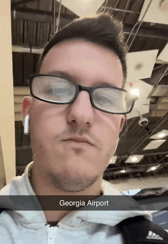 a man wearing glasses and ear buds with the caption georgia airport on the bottom