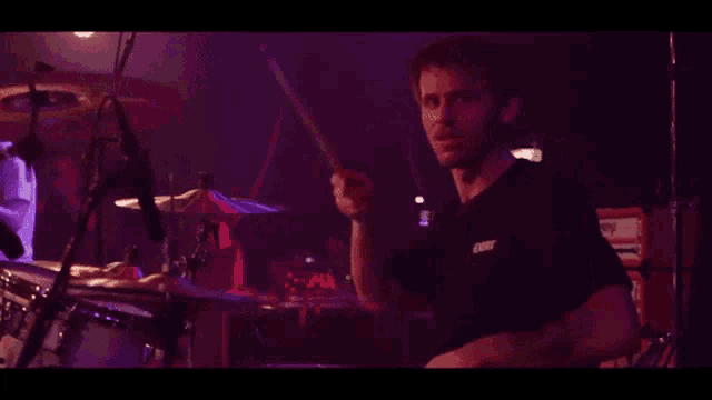 a man playing drums in a dark room with a shirt that says ' earl ' on it