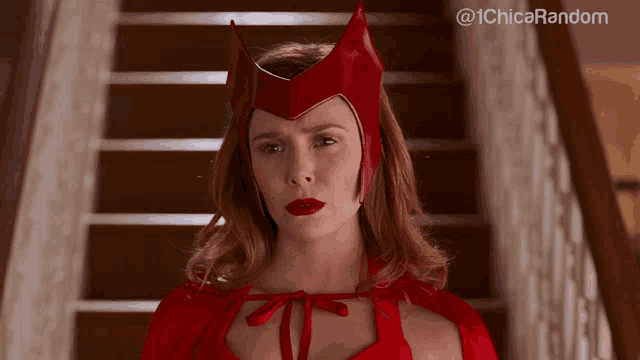 a woman in a red costume is standing on a set of stairs