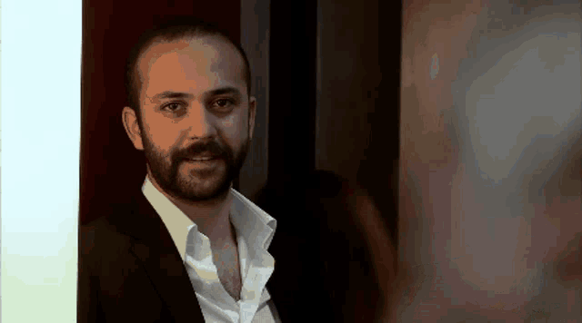 a man with a beard is wearing a suit and a white shirt