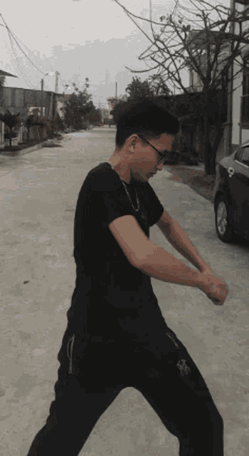 a man in a black shirt and black pants is standing on the street