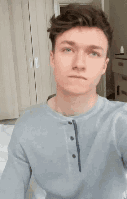 a young man wearing a grey shirt with buttons on the front