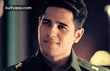 a man in a military uniform is smiling and looking to the side .
