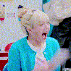 a woman wearing a blue sweater is yawning with her mouth open .